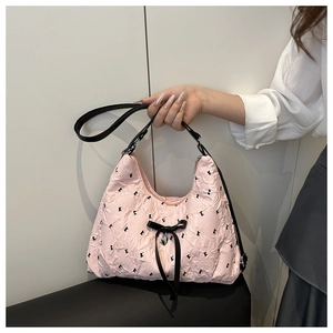 Pink pleated tote bag detail with black silk bow and heart-shaped metal pendant charm