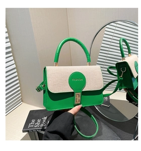 Dettaglio della borsa tessuta verde e beige con chiusura in metallo dorato e manico in pelle