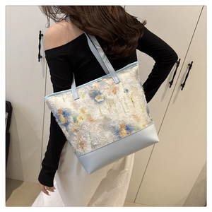 Detail of floral lace tote bag featuring blue leather trim and vibrant 3D flower embroidery