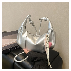 Detalle de bolso hobo plateado metalizado con diseño plisado y colgante de corazón