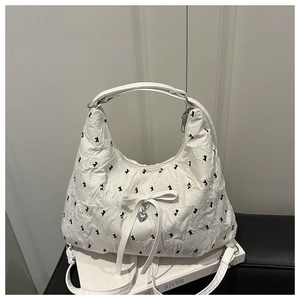 Close-up of white pleated shoulder bag featuring black patterns and silver heart pendant