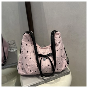 Close-up of pink pleated hobo bag with K-letter print, black bow, and silver heart charm