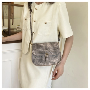 Detailed view of vintage grey-brown saddle bag with bronze buckle and adjustable strap