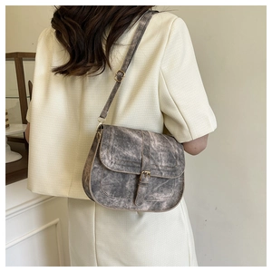 Retro charcoal saddle bag detail showing textured flap and brass buckle on female model