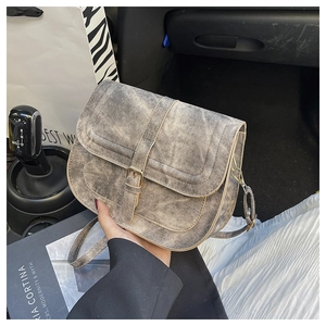 Close-up of grey washed denim saddle bag with metal buckle on a car seat