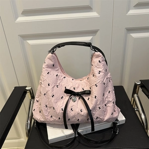 Pink pleated hobo underarm bag with black bow decoration and silver heart pendant detail