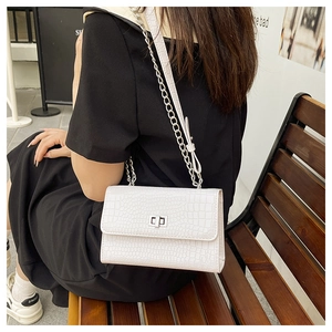 Detailed view of white crocodile pattern crossbody bag with silver metal twist lock