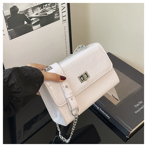 Detail of white crocodile pattern shoulder bag featuring a silver twist lock and chain strap
