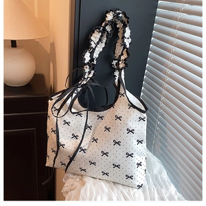 Close-up of pleated ruffled handle on a white canvas bag with black bow tie prints