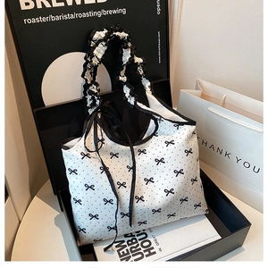 Close-up of a polka dot canvas tote with ruffled handle and black bow details