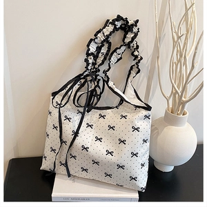 Detailed shot of cream polka dot tote bag with ruffled handles and black bow ribbons