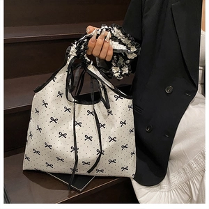 Detail of polka dot tote bag with pleated striped handle and black ribbon accents