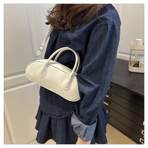 Nahaufnahme der cremefarbenen Mini-Boston-Tasche mit glattem Lackleder und Schultergurt