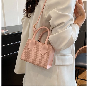 Detail of pink woven texture handbag with dual handles and adjustable shoulder strap