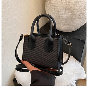 Detail of black mini crossbody bag featuring a unique diagonal woven texture and gold hardware