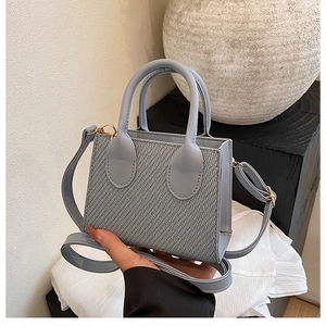 Close-up of light blue mini square bag showing textured panel and gold hardware