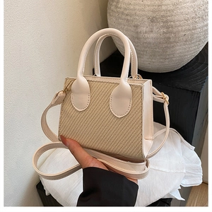 Detail of a mini beige woven crossbody bag with dual handles and gold hardware