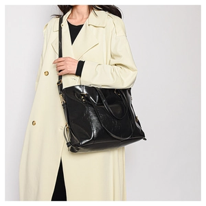 Detail shot of black leather tote bag with glossy finish and gold hardware on female model