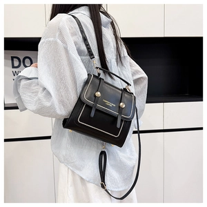Detail of black leather bag with pearl studs and golden hardware on a fashion model