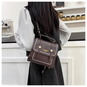 Detail of dark brown leather crossbody bag with pearl accents and gold hardware