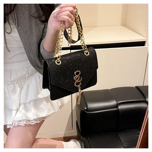 Detail of black sequined crossbody bag featuring golden tassel and metallic clasp