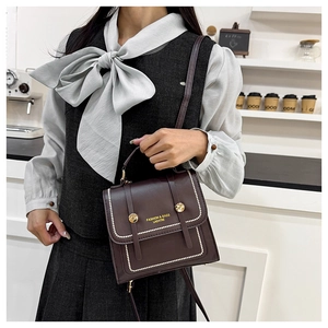 Macro shot of dark burgundy leather bag featuring pearl studs and golden metallic hardware