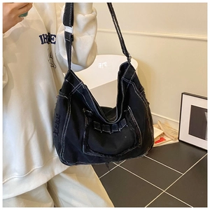 Détail du sac messager en toile noire avec coutures contrastées blanches et bords effilés