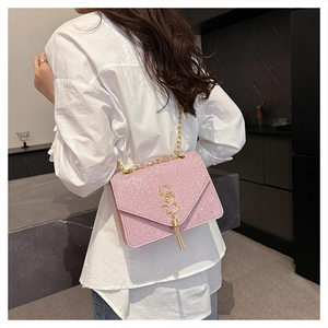 Close-up of pink glitter crossbody bag with gold chain strap and fringe tassel charm