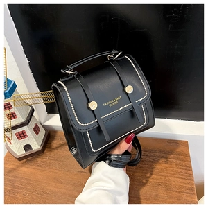 Detail of the black PU leather bag showing golden metal hardware and front logo print