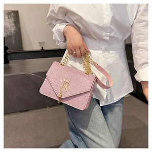 Detail of pink rhinestone crossbody bag with gold logo and chunky chain strap
