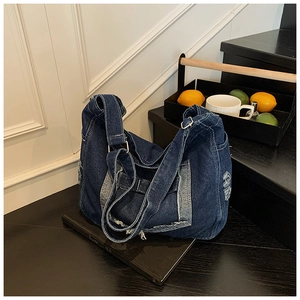 Vue détaillée du sac bandoulière en jean bleu foncé avec détails effilochés style vintage