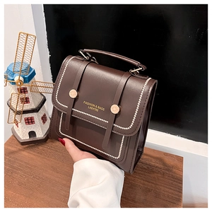 Detail of dark brown leather handbag with gold lettering and white beaded edge stitching