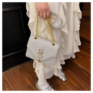 Close-up of a silver glitter crossbody bag with gold SSS buckle and thick chain strap