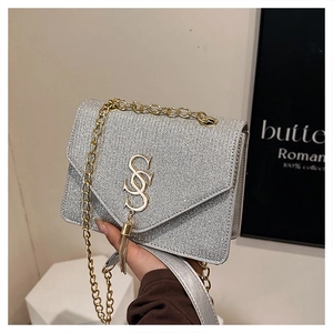 Detail of silver glitter crossbody bag featuring gold S logo and hanging metal tassels