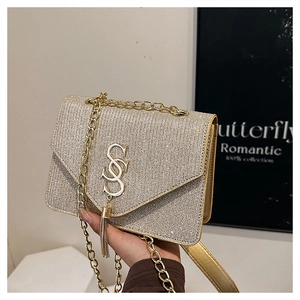 Detail of gold sequin envelope bag with S-shaped metal buckle and tassel chain
