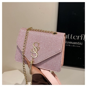 Detail of pink sequin crossbody bag featuring golden tassel and metal chain strap