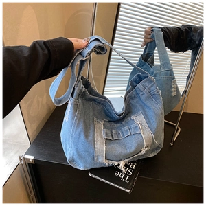 Détail du sac messager en denim lavé avec franges vintage et finitions à bords usés