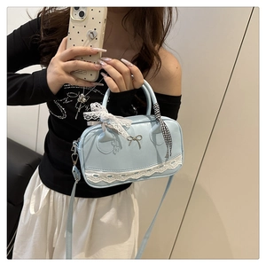 Detail of light blue Boston bag with white lace trim and metal bow charm handle