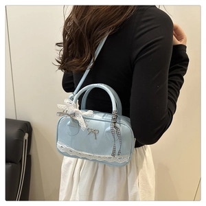 Detail of light blue bowling bag with lace trim, metal bow, and ribbon handle accents