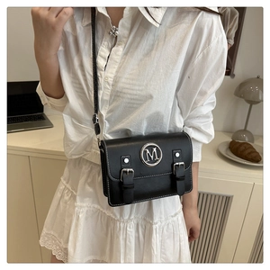 Close-up of black leather crossbody bag with silver M logo and contrast stitching detail
