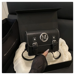 Detail of black leather square bag with silver M logo and premium gift packaging box