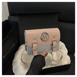 Close-up of pink and silver crossbody bag with metallic M logo in a black gift box