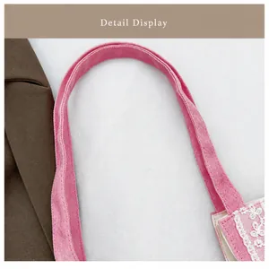 Detalle del bolso tote de lona rosa con costuras y elegante adorno de encaje blanco