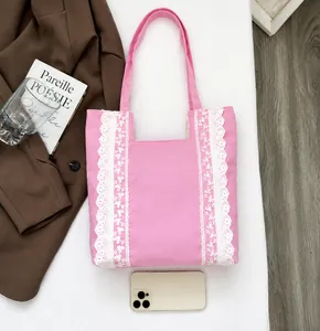 Bolso tote de lona rosa con encaje junto a un smartphone para referencia de tamaño