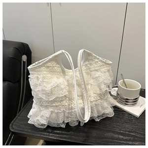 Dettaglio di balze in pizzo bianco a strati su una grande borsa tote con manici