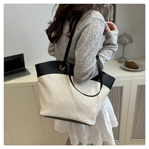 Detailed view of the woven tote bag with black leather straps and gold ring hardware