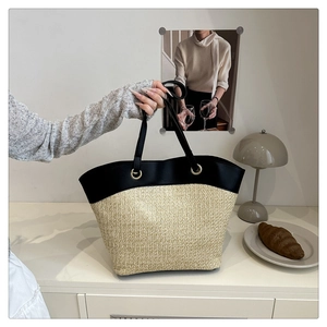Detail of hand-woven straw tote with black leather trim and golden metal eyelets