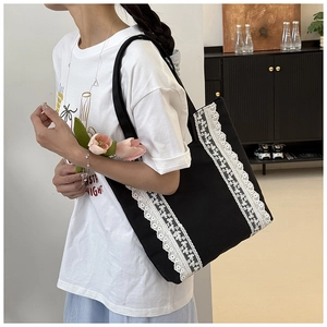 Détail du grand sac cabas en toile noire orné de dentelle blanche et poignées élégantes
