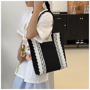 Vue détaillée du sac cabas en toile noire avec bordures en dentelle blanche élégante