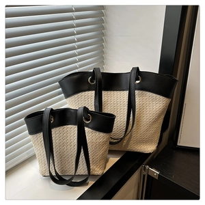 Detail view of large and small woven tote set with black leather straps and metal eyelets